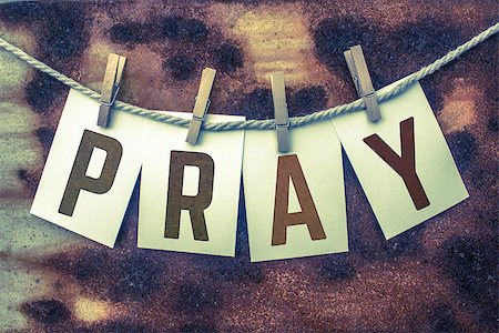 The word PRAY stamped on card stock hanging from old twine and clothes pins over a rusty vintage background. Stock Photo - Budget Royalty-Free & Subscription, Code: 400-08707402