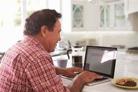 simsearch:400-08737249,k - Senior Hispanic Man Sitting At Home Using Laptop Foto de stock - Super Valor sin royalties y Suscripción, Código: 400-08737248