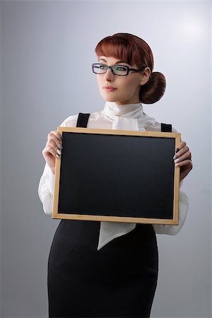 simsearch:400-04791676,k - Beautiful young woman in glasses with small blackboard. Teacher wearing blouse and skirt. Copy space. Over grey background. Stock Photo - Budget Royalty-Free & Subscription, Code: 400-08731059