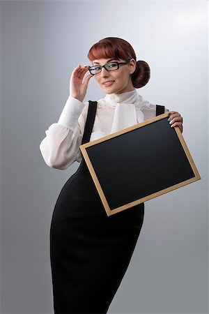 simsearch:400-04791676,k - Beautiful young woman in glasses with small blackboard. Teacher wearing blouse and skirt. Copy space. Over grey background. Stock Photo - Budget Royalty-Free & Subscription, Code: 400-08731060