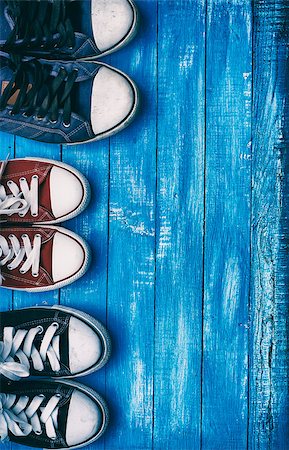 Three pairs of old sneakers on a blue shabby wooden vertical background, top view Foto de stock - Super Valor sin royalties y Suscripción, Código: 400-08731547