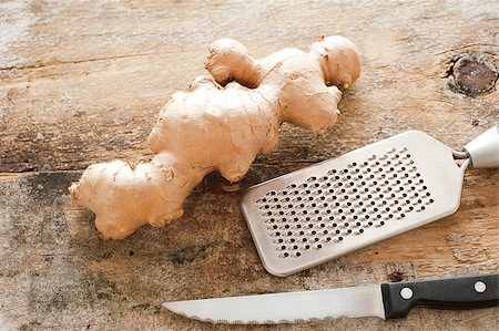 stockarch (artist) - Section of whole raw root ginger on a rustic table with a stainless steel, grater and knife ready to be prepared as a healthy spicy ingredient for cooking Foto de stock - Royalty-Free Super Valor e Assinatura, Número: 400-08732856