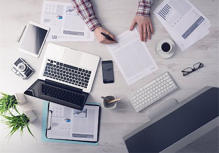 simsearch:400-09222181,k - Businessman working at office desk and signing a document, computers and paperwork all around, top view Fotografie stock - Microstock e Abbonamento, Codice: 400-08749487