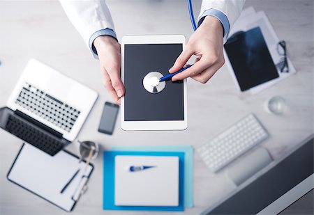 simsearch:400-08751444,k - Doctor checking heartbeat on a digital tablet using a stethoscope, desktop with medical equipment on background, top view Photographie de stock - Aubaine LD & Abonnement, Code: 400-08749513