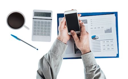 Businessman at desk using a touch screen smart phone, calculator and financial report, hands top view Stock Photo - Budget Royalty-Free & Subscription, Code: 400-08749633