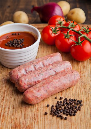 simsearch:400-07713408,k - Raw beef sausages with tomatoes and sause on kitchen wooden board. Potatoes and pepper Stock Photo - Budget Royalty-Free & Subscription, Code: 400-08759232