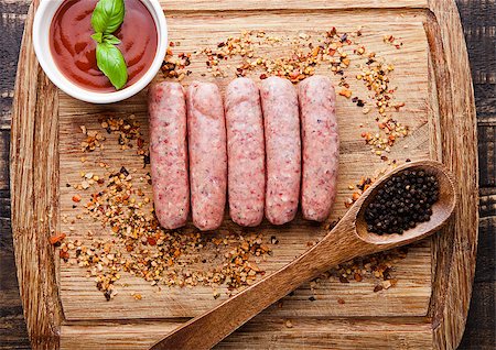 simsearch:400-07713408,k - Raw beef sausages with pepper spoon and sause on board. Spices for beef. Basil in sause Stock Photo - Budget Royalty-Free & Subscription, Code: 400-08759233