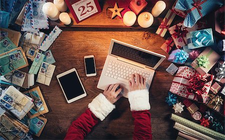 simsearch:400-08749588,k - Hi-tech Santa Claus working at his desk and typing on a laptop surrounded by gift boxes and Christmas letters, hands top view Stock Photo - Budget Royalty-Free & Subscription, Code: 400-08751367
