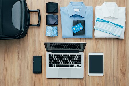 desktop from above - Planning a business trip: bag, formal clothing, credit cards and plane tickets on a desk with laptop, smartphone and tablet, traveling and technology concept Stock Photo - Budget Royalty-Free & Subscription, Code: 400-08751440