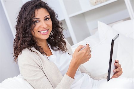 simsearch:400-07112758,k - Beautiful young Latina Hispanic woman smiling, relaxing and drinking a cup of coffee or tea using tablet computer Fotografie stock - Microstock e Abbonamento, Codice: 400-08774190