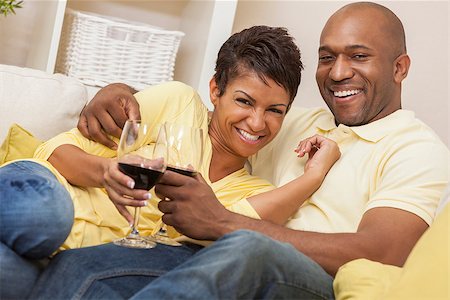 A happy African American man and woman couple in their thirties sitting at home together smiling and drinking glasses of red wine. Stock Photo - Budget Royalty-Free & Subscription, Code: 400-08775616