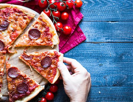 pepperoni - Tasty Hand Made Tomatoes and Pepperoni Pizza with italian style recipe over a wooden table with a Dramatic light. Photographie de stock - Aubaine LD & Abonnement, Code: 400-08772118