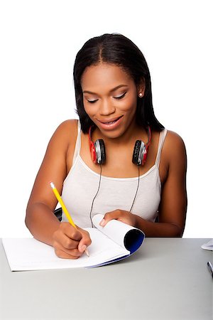 Cute beautiful happy smiling teenage student doing homework writing in notebook sitting at desk, on white. Stock Photo - Budget Royalty-Free & Subscription, Code: 400-08773032
