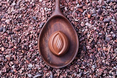 Chocolate candy in a wooden spoon on a crushed raw cocoa beans, nibs background. Copy space Top view Photographie de stock - Aubaine LD & Abonnement, Code: 400-08773849