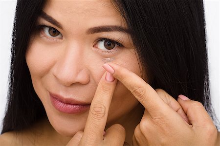 simsearch:6113-07565306,k - Closeup of woman putting contact lenses over white background. Lady putting lenses and looking at camera. Stock Photo - Budget Royalty-Free & Subscription, Code: 400-08785410