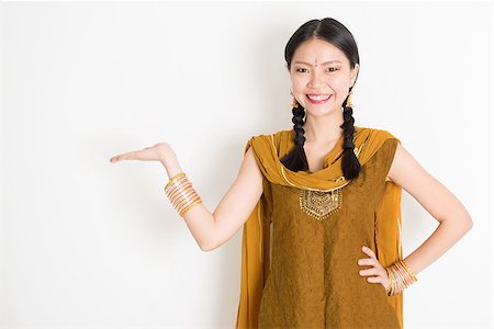 Portrait of young mixed race Indian Chinese female in traditional punjabi dress hand holding somethings, standing on plain white background. Stock Photo - Budget Royalty-Free & Subscription, Code: 400-08787345