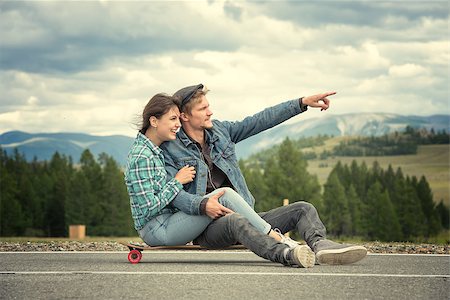 rammellzee (artist) - The guy with the girl sit on a longboard. A man shows his hand forward. The road in the mountains Stock Photo - Budget Royalty-Free & Subscription, Code: 400-08795355