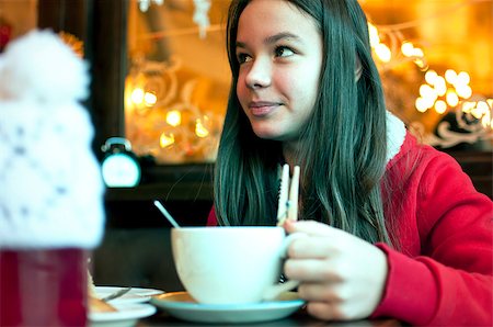 Girl with a cup of tea in a cafe eating Christmas cookies and looks aside Stockbilder - Microstock & Abonnement, Bildnummer: 400-08795689