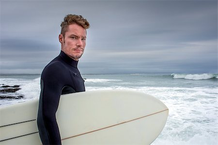 Portrait of a surfer with his surfboard under his arm as he stands by the beach at "The Point" in Jeffreys Bay. Photographie de stock - Aubaine LD & Abonnement, Code: 400-08795833