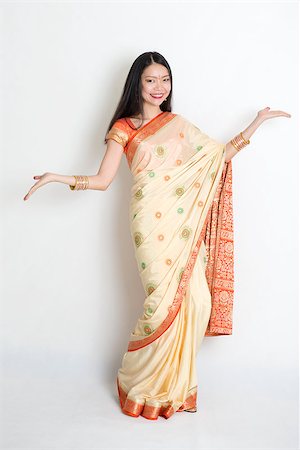 Portrait of young mixed race Indian Chinese woman in traditional sari dress dancing, on plain background. Stock Photo - Budget Royalty-Free & Subscription, Code: 400-08790033