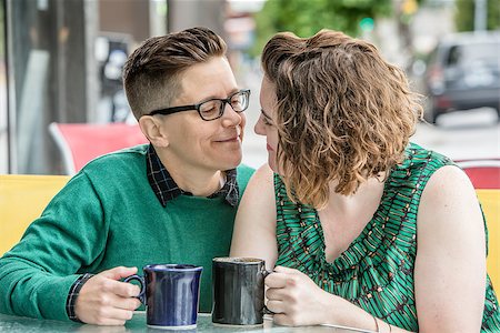 Romantic lesbian couple at bistro outdoors with coffee mugs in hand Stock Photo - Budget Royalty-Free & Subscription, Code: 400-08790671