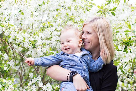 simsearch:400-08787277,k - young smiling mother holding her cute cheerful son and enjoying blooming trees in the park at spring Stock Photo - Budget Royalty-Free & Subscription, Code: 400-08792467