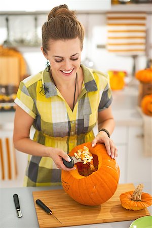 simsearch:400-07172678,k - Frightful Treats on the way. happy young woman in the Halloween decorated kitchen prepare big orange pumpkin for carving Photographie de stock - Aubaine LD & Abonnement, Code: 400-08792505