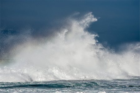 A massive wave crashes against a reef in the ocean sending water spraying high up in the air. Stock Photo - Budget Royalty-Free & Subscription, Code: 400-08793045