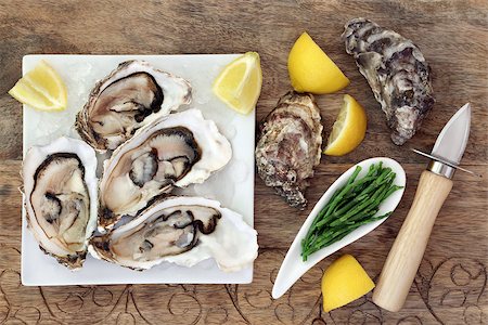 superfood dinners - Oysters on crushed ice on a square china plate with oyster knife, samphire and lemon fruit on old wooden background. Stock Photo - Budget Royalty-Free & Subscription, Code: 400-08808605