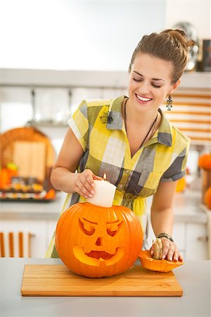 simsearch:400-07172678,k - Frightful Treats on the way. happy modern housewife in the Halloween decorated kitchen putting candle inside a big orange pumpkin Jack-O-Lantern Photographie de stock - Aubaine LD & Abonnement, Code: 400-08809164