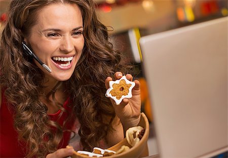 Smiling young woman showing christmas cookies while having video chat on laptop Foto de stock - Super Valor sin royalties y Suscripción, Código: 400-08809165