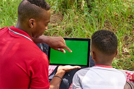 Happy black people in city park. African american family with young man and child using tablet computer for internet. Laptop monitor with green screen Stock Photo - Budget Royalty-Free & Subscription, Code: 400-08816129