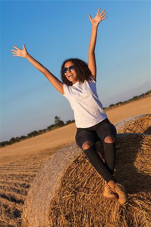 farm girl jeans - A beautiful, happy mixed race African American female girl child teenager young woman celebrating arms raised in sunshine wearing sunglasses and smiling with perfect teeth Photographie de stock - Aubaine LD & Abonnement, Code: 400-08818966