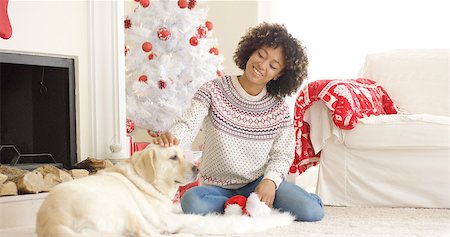 dog christmas light - Pretty smiling young woman stroking her golden retriever dog as they relax together on the floor in front of a Christmas tree and hearth Stock Photo - Budget Royalty-Free & Subscription, Code: 400-08810058
