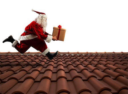 Santa Claus runs with a big present on a house roof Stock Photo - Budget Royalty-Free & Subscription, Code: 400-08812034