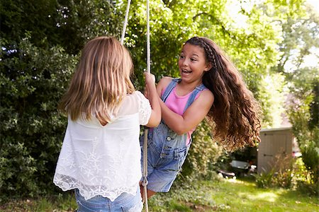 Two Girls Playing Together On Tire Swing In Garden Stock Photo - Budget Royalty-Free & Subscription, Code: 400-08837792