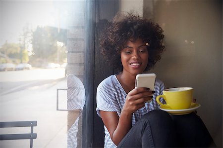 deli window - Young black woman using smartphone beside a window in a cafe Stock Photo - Budget Royalty-Free & Subscription, Code: 400-08838069