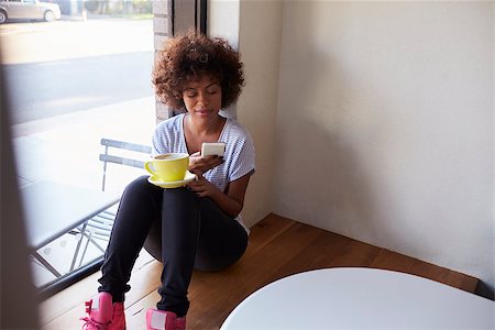deli window - Young black woman sitting by window in cafe using smartphone Stock Photo - Budget Royalty-Free & Subscription, Code: 400-08838095