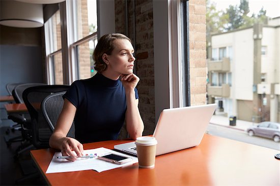 Thoughtful Businesswoman Working On Laptop By Window Stock Photo - Royalty-Free, Artist: MonkeyBusinessImages, Image code: 400-08838512