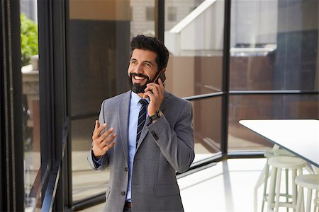 simsearch:400-08838779,k - Smiling middle aged Hispanic businessman on phone in office Stock Photo - Budget Royalty-Free & Subscription, Code: 400-08838805