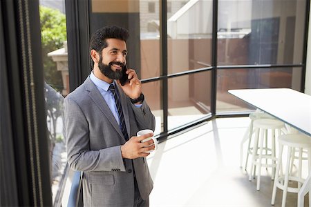 simsearch:400-08838779,k - Middle aged Hispanic businessman using phone and holding cup Stock Photo - Budget Royalty-Free & Subscription, Code: 400-08838806