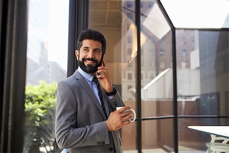 simsearch:400-08838779,k - Middle aged Hispanic businessman using phone and holding cup Stock Photo - Budget Royalty-Free & Subscription, Code: 400-08838807