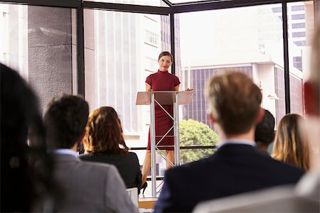 simsearch:400-08838779,k - Young woman standing at lectern presenting business seminar Stock Photo - Budget Royalty-Free & Subscription, Code: 400-08838949