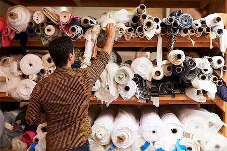 fashion store manager - Man reaching to select fabric from storage shelves Stock Photo - Budget Royalty-Free & Subscription, Code: 400-08839060