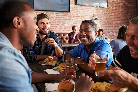 Male Friends Eating Out In Sports Bar With Screens In Behind Foto de stock - Super Valor sin royalties y Suscripción, Código: 400-08839151