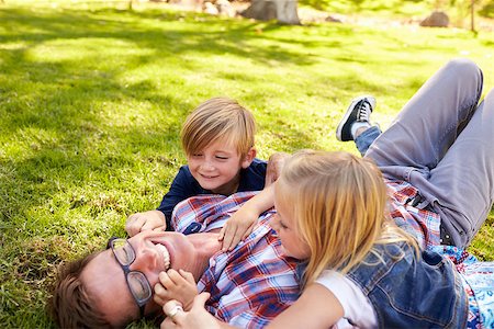 simsearch:400-04042848,k - Two kids playing with their dad, lying in a park, side view Fotografie stock - Microstock e Abbonamento, Codice: 400-08839649