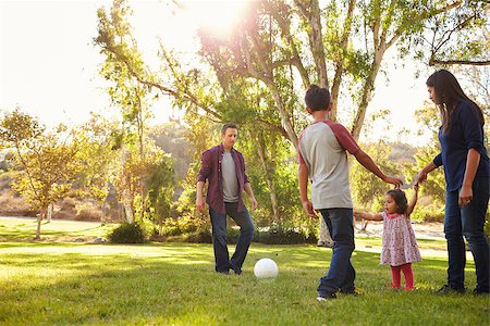 family playing soccer - Young mixed race family playing with ball in a park, backlit Stock Photo - Budget Royalty-Free & Subscription, Code: 400-08839662