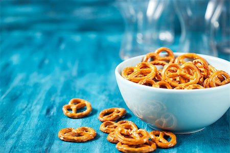 simsearch:400-08832368,k - Salty snacks mini pretzels in bowl on blue wooden table Stock Photo - Budget Royalty-Free & Subscription, Code: 400-08831411