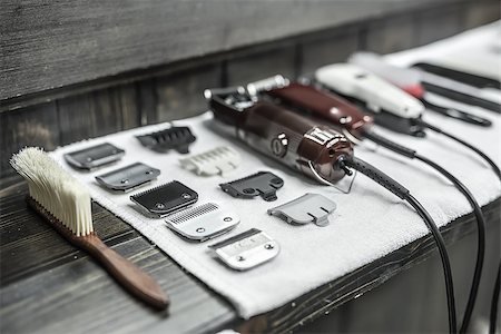 Closeup photo on the wide aperture of the hairdresser accessories: a wooden hairbrush, clipper blades, hair clippers and hair combs. They lies on the white towel and the dark wooden rack. Horizontal. Foto de stock - Super Valor sin royalties y Suscripción, Código: 400-08831927