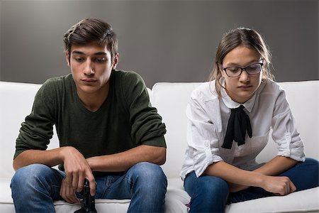 sibling sad - portrait of a couple of brother and sister sad or worried about something caught in the middle of their daily life with a jpypad on the sofa Stock Photo - Budget Royalty-Free & Subscription, Code: 400-08832311